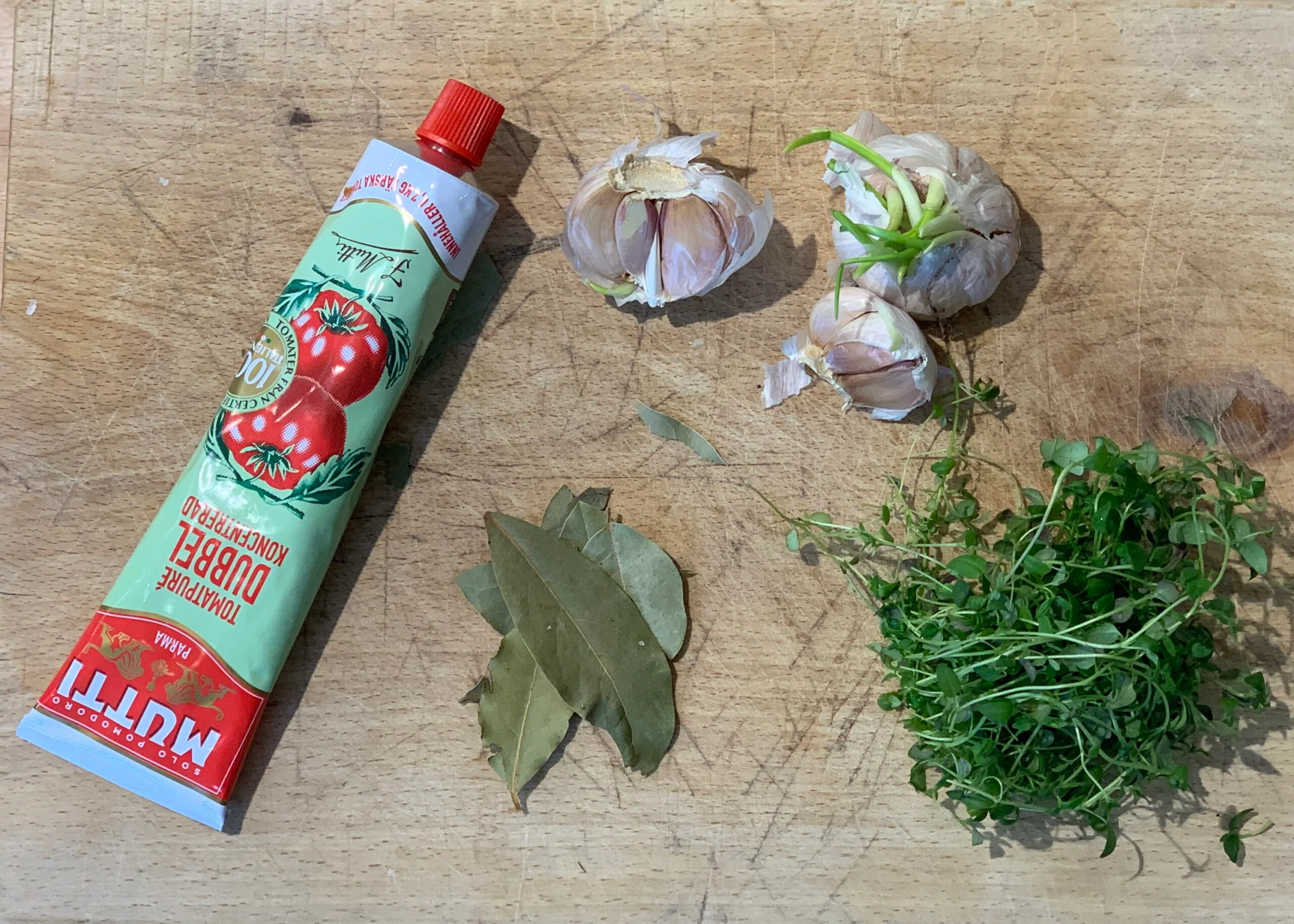 Tomatpure, hvitløk, timian og laubærblader på trefjøl.
