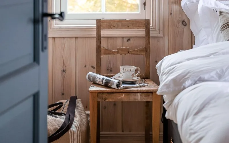 Bondestol ses igjennom en dør. På stolen står det en tekopp og ligger et blad.