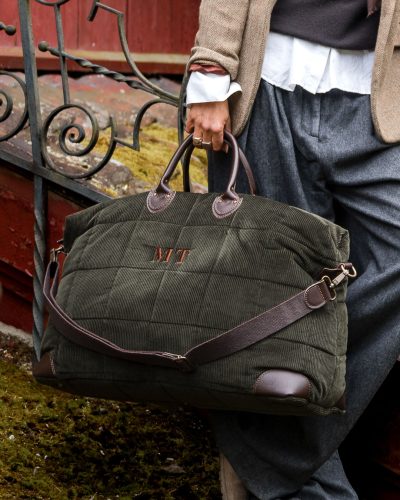 Skogsgrønn reiseveske i vattert cordfløyel med brune skinndetaljer.