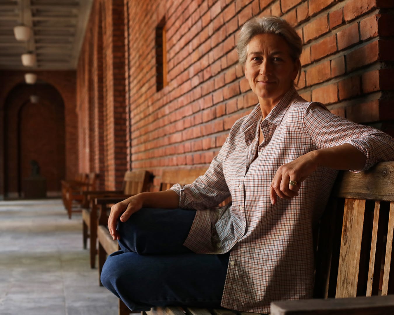 Kine i smårutet India Boyfrienskjorte sittende på benk utenfor en Vigelandmuseet. Stemningen i bildet er mørk og høstaktig.